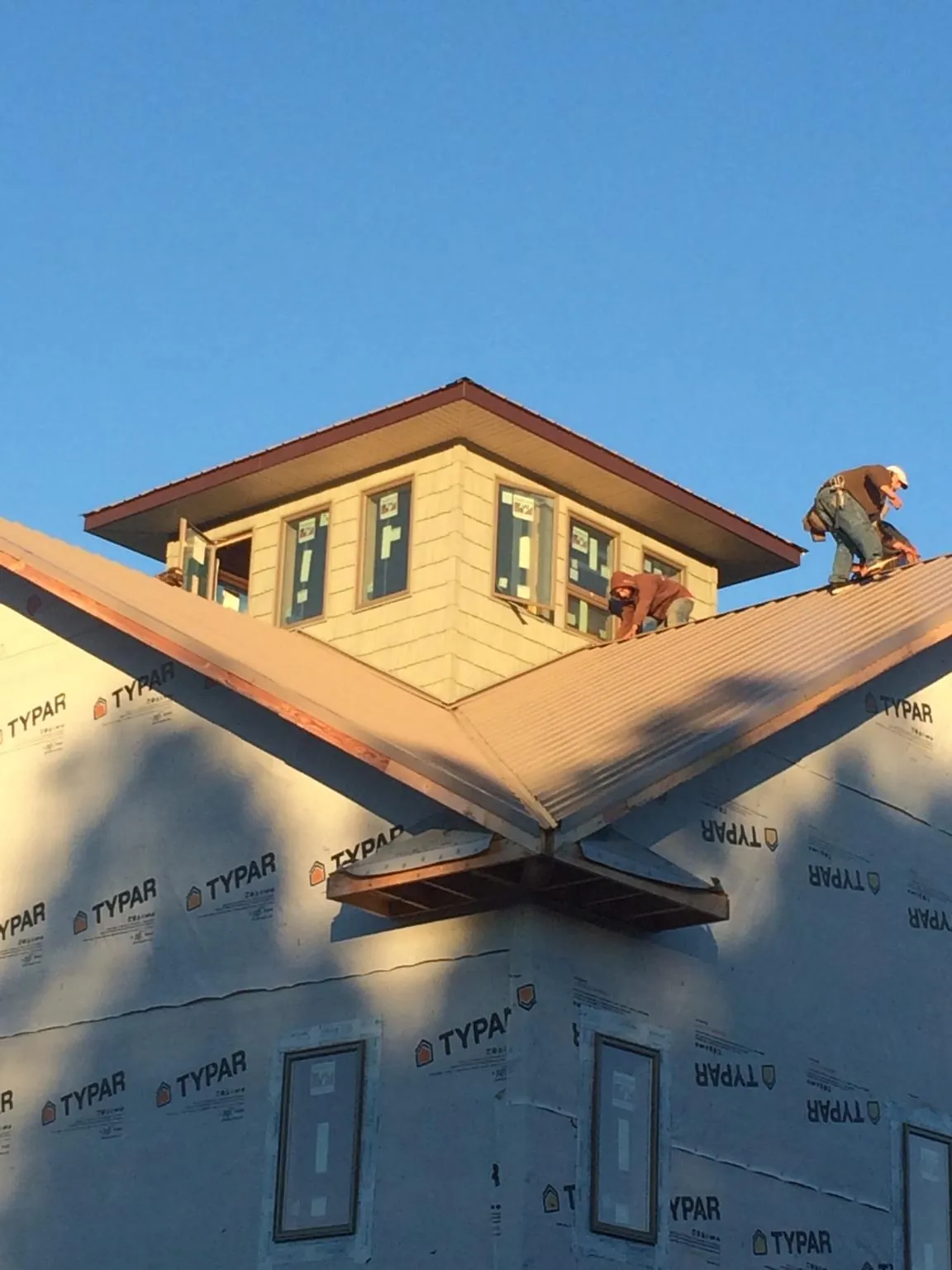 Roofers working around a rooftop cupola on a new metal roof at sunset — Roof Waterproofing in Hastings by Roofing Brothers